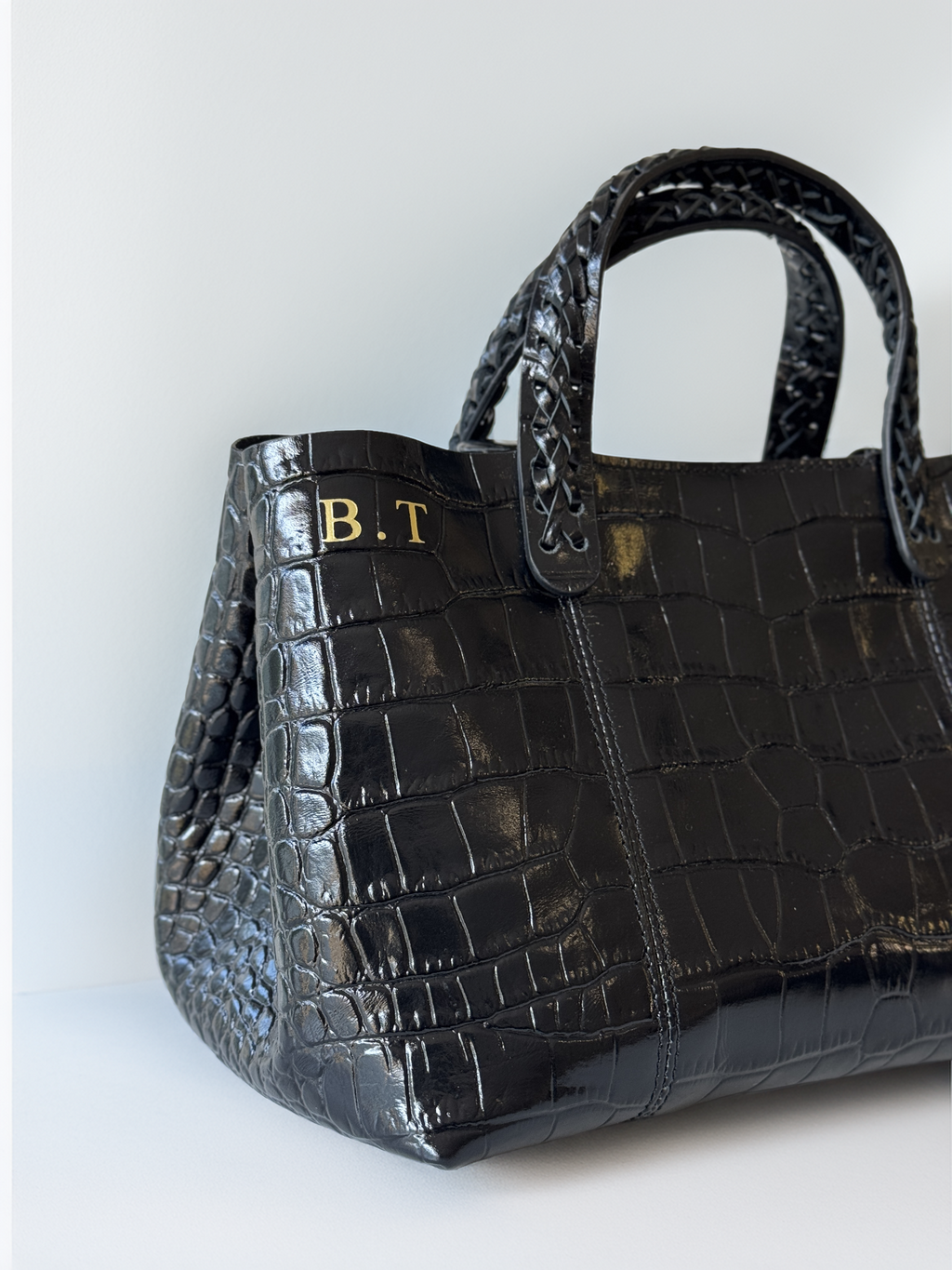 Black crocodile-patterned handbag with 'B.T.' initials